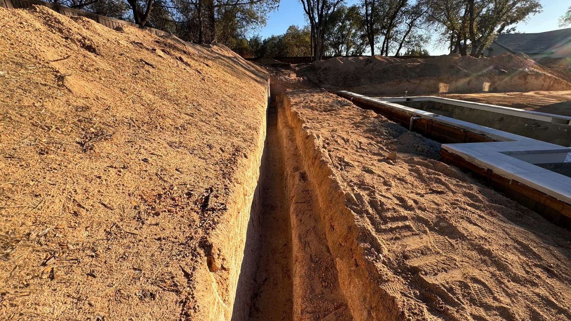 Long, precise footing excavation trench cut alongside a residential foundation
